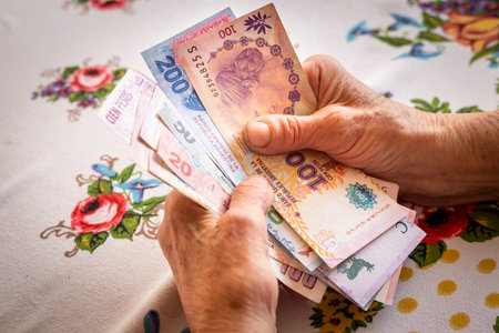 Argentine money pesos, a pensioner holds several banknotes in her hand, Financial problems of seniors, inflation and poverty in Argentinaの写真素材