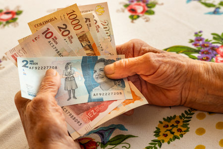 Colombian peso, a pensioner holds several banknotes in her hand, Financial problems of seniors, inflation and poverty in Colombiaの写真素材