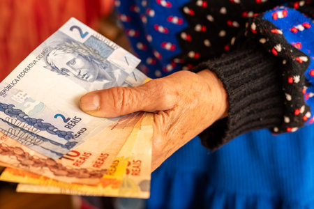 Brazilian money, a pensioner holds several reais banknotes in her hand, Financial problems of seniors, low pensions in Brazilの写真素材