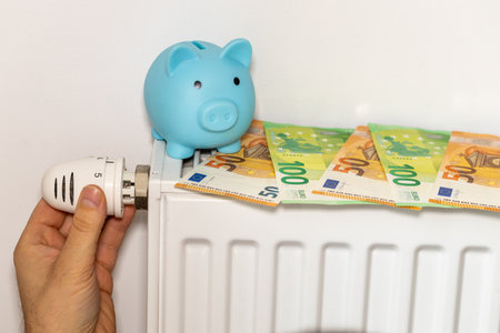 costs of heating apartments in winter in the European Union, energy and economic concept, hand unscrewing the radiator, piggy bank and euro moneyの写真素材
