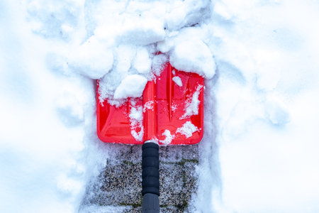 Snow removal in winter, Snowfall, Red shovel lying in the snow. Seasonal concept, difficult weather conditionsの写真素材