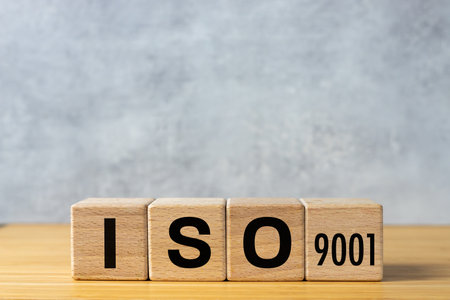 ISO 9001 certified concept. ISO text on wooden cubes. Gray background. Quality control.の写真素材
