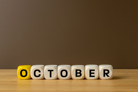Symbol of October. Conceptual word October on wooden blocks standing table on beautiful brown background, copy space. Beginning of autumn. sales in stores, season, colorful leaves, increase in coldsの写真素材