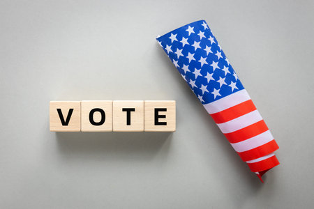 vote 2024, American flag and written word vote on wooden blocks. Gray background, flat layの写真素材