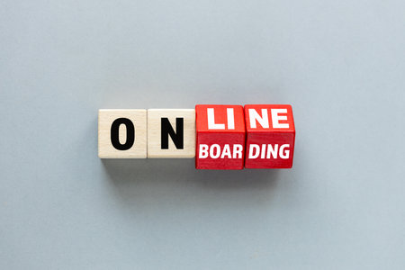 Online onboarding symbol. Rotated wooden cubes form the word onboarding online. Beautiful gray...