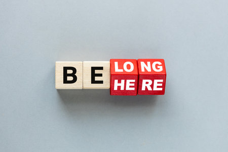 Here belong symbol. rotating dice changing the word "be here" to "belong". Beautiful gray background. Business, belonging and be here belong concept.の写真素材