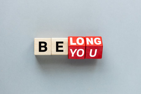 Symbol Be you, belong. Rotating cubes and changing the word "be you" to "belong". Gray background. Business concept, belonging and Be you, belong. Flat lay. Copy space.の写真素材