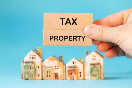 Tax Property written on wooden blocks. Miniature house. conceptual slogan. Property value tax. Beautiful blue backgroundの写真素材