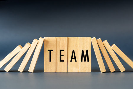 A cohesive and harmonious team. Evenly standing blocks with the word Team and the others falling over. Concept for business teamwork, recruitment and leadershipの写真素材