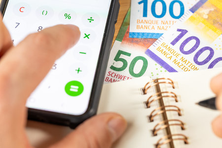 Swiss francs, Counting on smartphone calculator, CHF money, notes in notebook. Financial settlement, Household budget, Taxes, Switzerland currency exchange rate, Business Financial Analysis Conceptの写真素材