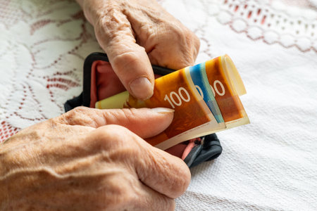 An elderly lady takes Israeli shekels out of her wallet. Financial concept. The economic situation...
