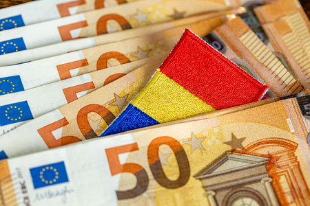 Romanian flag sticking out from between Euro banknotes. Financial concept. Romania's preparations for joining the Eurozoneの写真素材