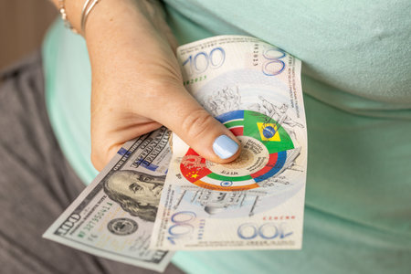 A woman holds a sample of the BRICS common currency and a 100-dollar bill. Currency systems concept