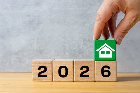 The year 2026. A hand forms a green house icon over the date 2026. Business concept. Real estate...