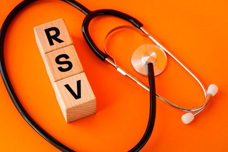 RSV viruses. Flu season. Medical concept. RSV written on wooden blocks and a lying stethoscope. Orange background, Copy spaceの写真素材