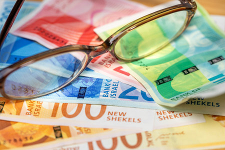 Israel money. Old fashioned glasses lying on Israeli shekels. Financial and business concept. close upの写真素材