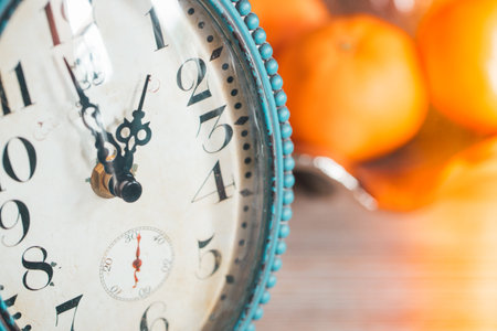 Old-style clock ticking away. Fruit platter in the background. Close-up. Retro stylesの写真素材