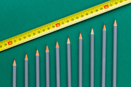 Growing bars going up. Gray pencils pointed symbolizing upward trends. Measuring tape symbolizing...
