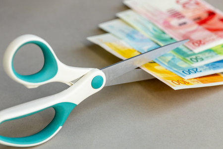 Money Israel. Scissors cutting Israeli shekels. Decline in value. Financial business concept. Cost...
