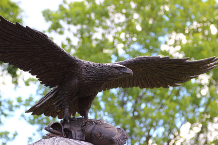 A bronze eagle taking off a stone monument with cuirass of a dead soldier. Russia, Borodino.