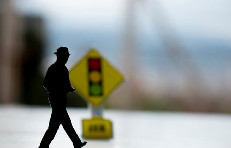 Silhouette of a man walking on the road with traffic lightの写真素材