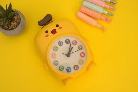Yellow alarm clock and stationery on yellow background. Back to school concept.
