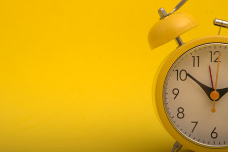 Yellow alarm clock on a yellow background with copy space for text.の写真素材