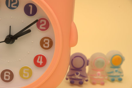 Retro alarm clock and toys isolated on a yellow background. Time concept.