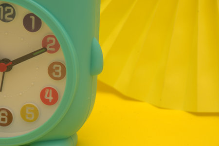 Green alarm clock on yellow background with copy space. Time concept.のeditorial素材