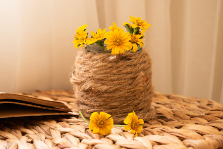 Bouquet of yellow flowers on a wicker chair with a bookの写真素材