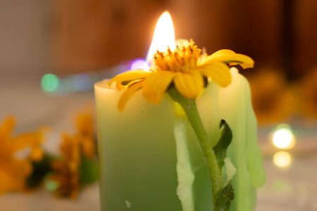 Burning candle with yellow flowers on the table, close-upの写真素材