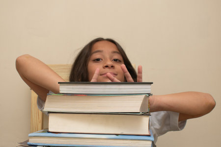 little girl sitting on a stack of books and looking at the camera