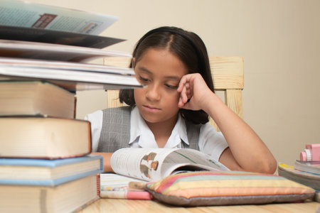 Portrait of a young girl studying at the desk with books.の写真素材