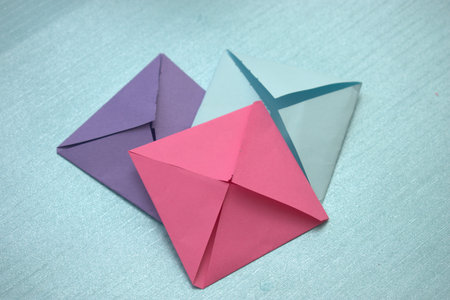 Colorful origami paper envelopes on blue background, close up