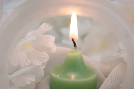 Candle and flowers on white background, soft focus, close upの写真素材