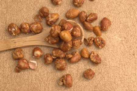 Roasted peanuts with wooden spoon on a brown background, close upの写真素材