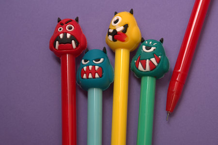 Pencils with funny monsters on purple background. Top view.の写真素材