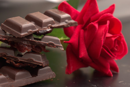 Dark chocolate and red rose on a black background. Selective focus.の写真素材