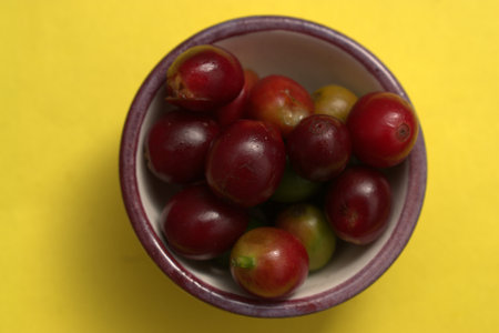 Coffee beans in a bowl on a yellow background, top viewの写真素材