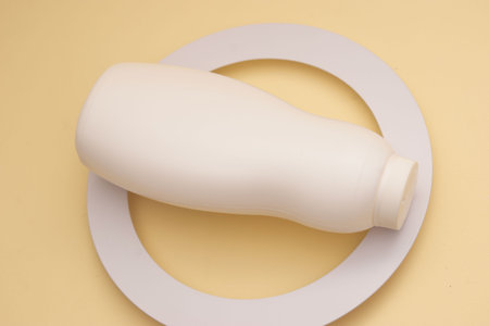White plastic bottle on a round white plate on a yellow background.の写真素材