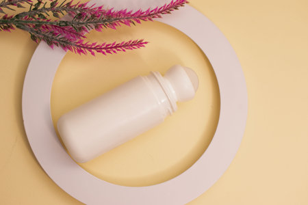 Cosmetic bottle and pink flower on yellow background. Flat lay.