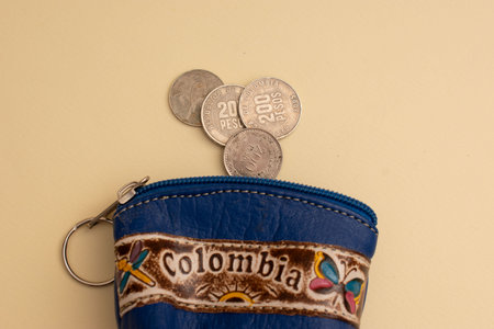 Coins in a blue leather wallet on a beige background.