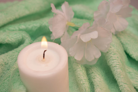 Spa and wellness setting with candle, towel and jasmine flowersの写真素材