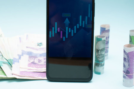 Smartphone with stock market graph and euro banknotes on blue background
