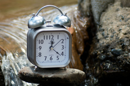 Alarm clock on the rock in the stream. Time concept.の写真素材