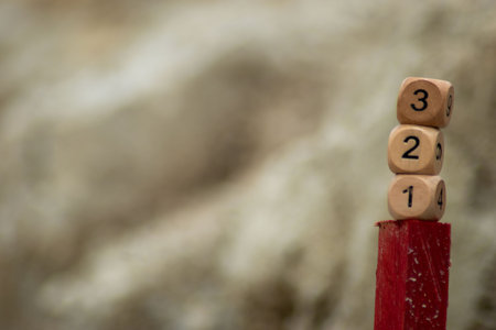 Wooden cubes with numbers on top of a red wooden fenceの写真素材