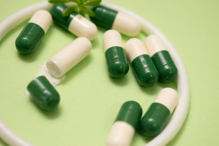Green and white medical capsules on a green background with copy space.