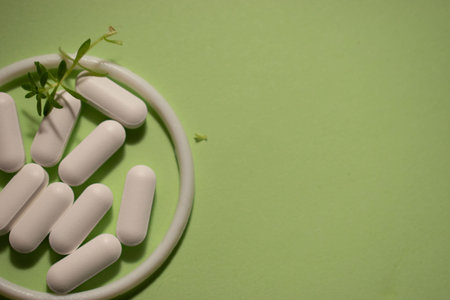 White pills on green background with copy space. Top view. Health care concept.の写真素材