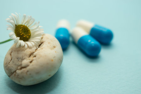 Pills and daisy flower on blue background. Copy space.の写真素材