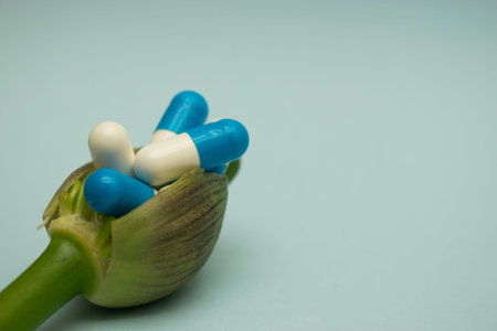 Pills and capsules on a green stem of a plant on a blue background